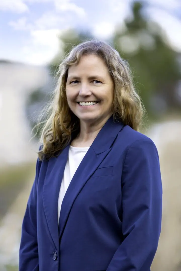 A woman in a blue jacket smiling for the camera.