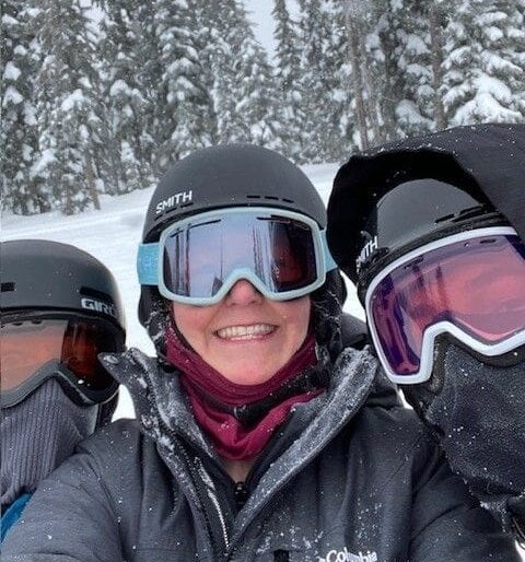 Three people wearing ski goggles and helmets on a snowy slope.