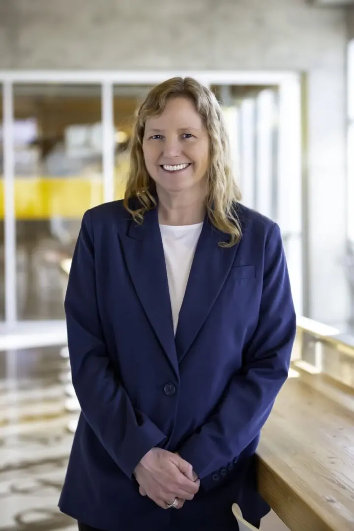 A woman in a blue suit standing next to a glass wall.