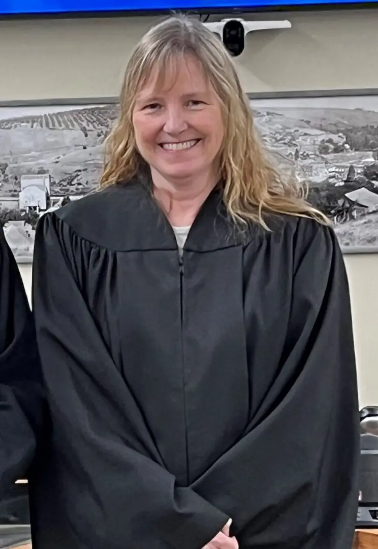 A woman in black gown standing next to wall.